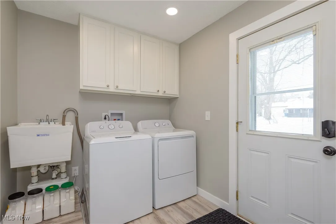 Washroom with light wood-style floors, washer and clothes dryer, recessed lighting, and cabinet space