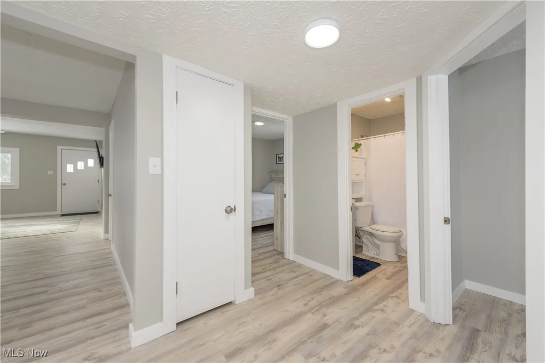 Corridor featuring a textured ceiling and light wood-style floors