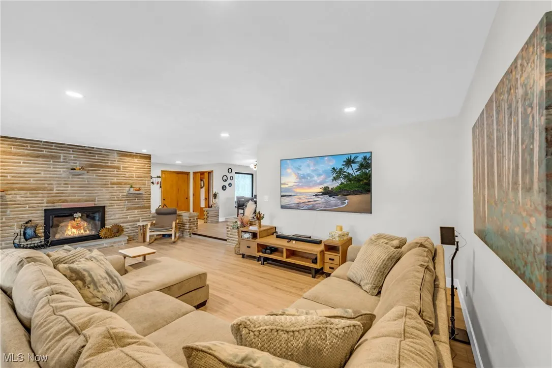 Living area with recessed lighting, wood finished floors, and a large fireplace