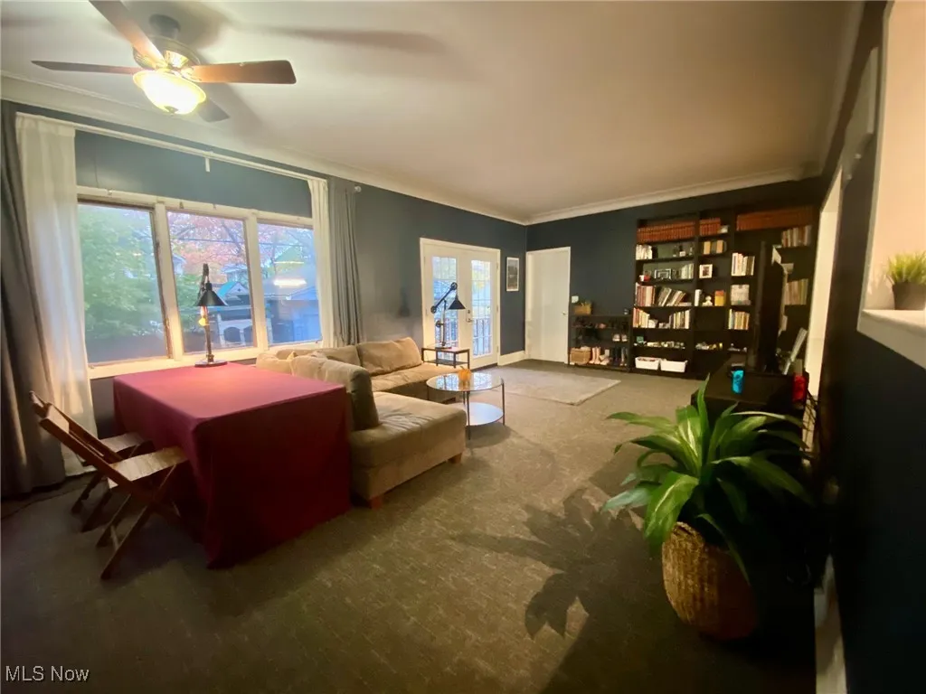 Carpeted living area featuring ornamental molding and ceiling fan