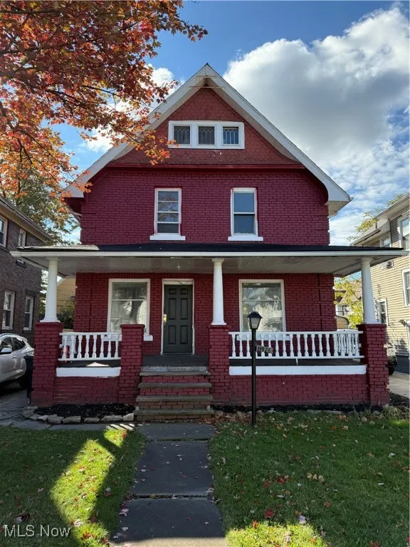 Traditional style home with a porch, brick siding, and a front yard