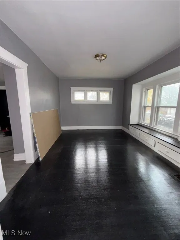 Empty room with dark wood finished floors and healthy amount of natural light
