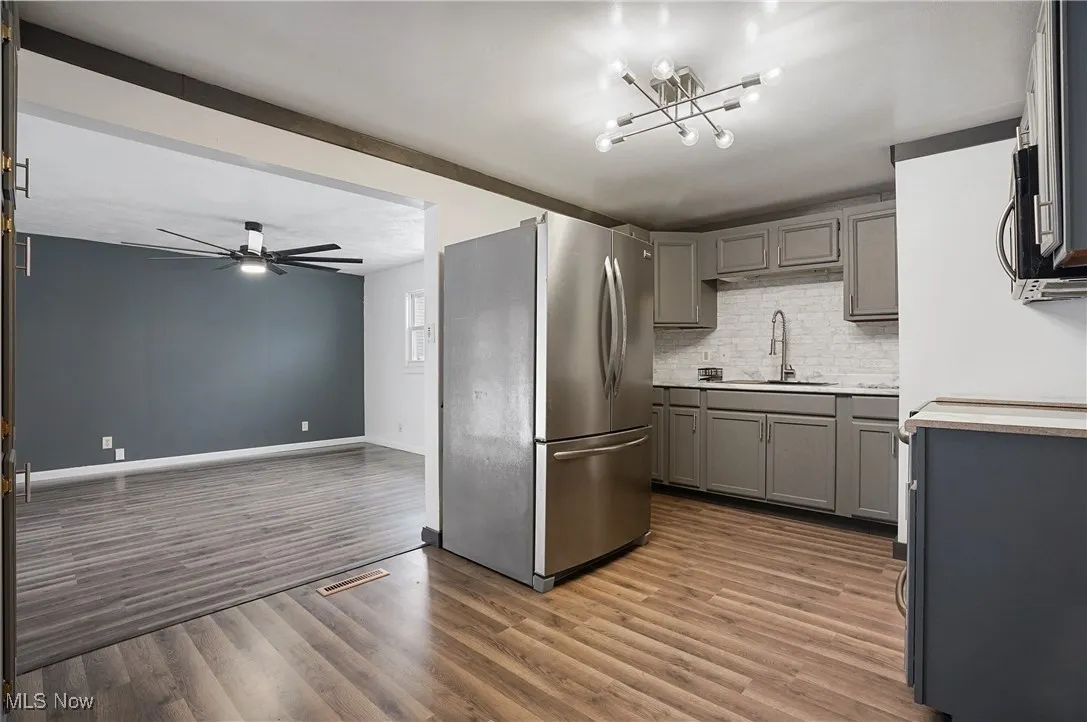 Kitchen featuring gray cabinetry, stainless steel appliances, light countertops, ceiling fan, and dark wood-style floors