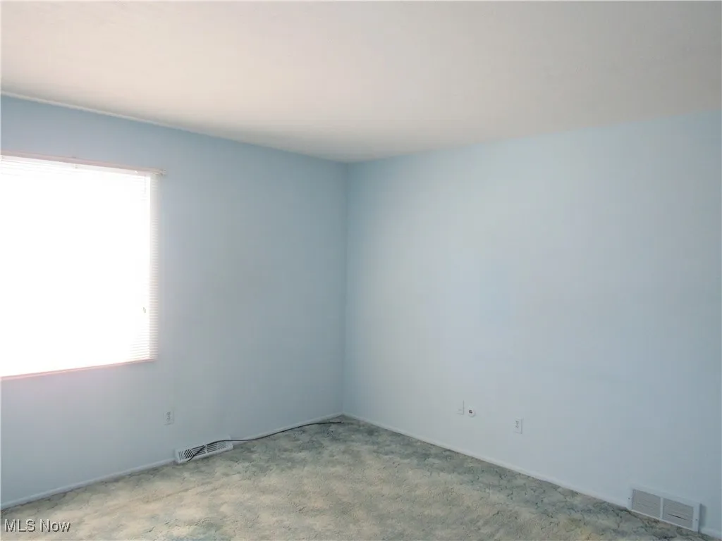 Spare room featuring carpet flooring and baseboards