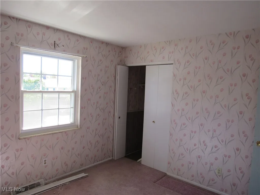 Carpeted empty room featuring wallpapered walls