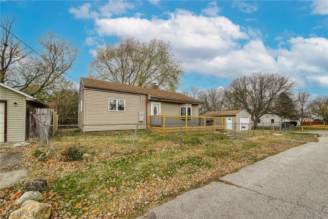 Bungalow with a wooden deck, a fenced front yard, and a chimney