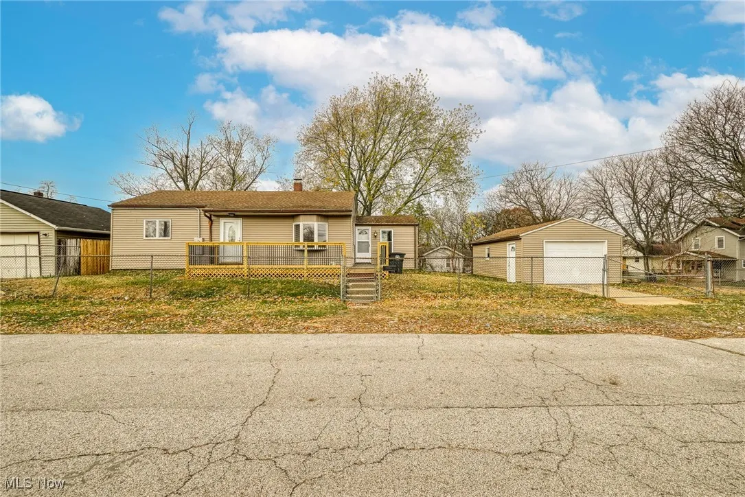 View of front of home featuring a detached garage, an outbuilding, a chimney, and a deck
