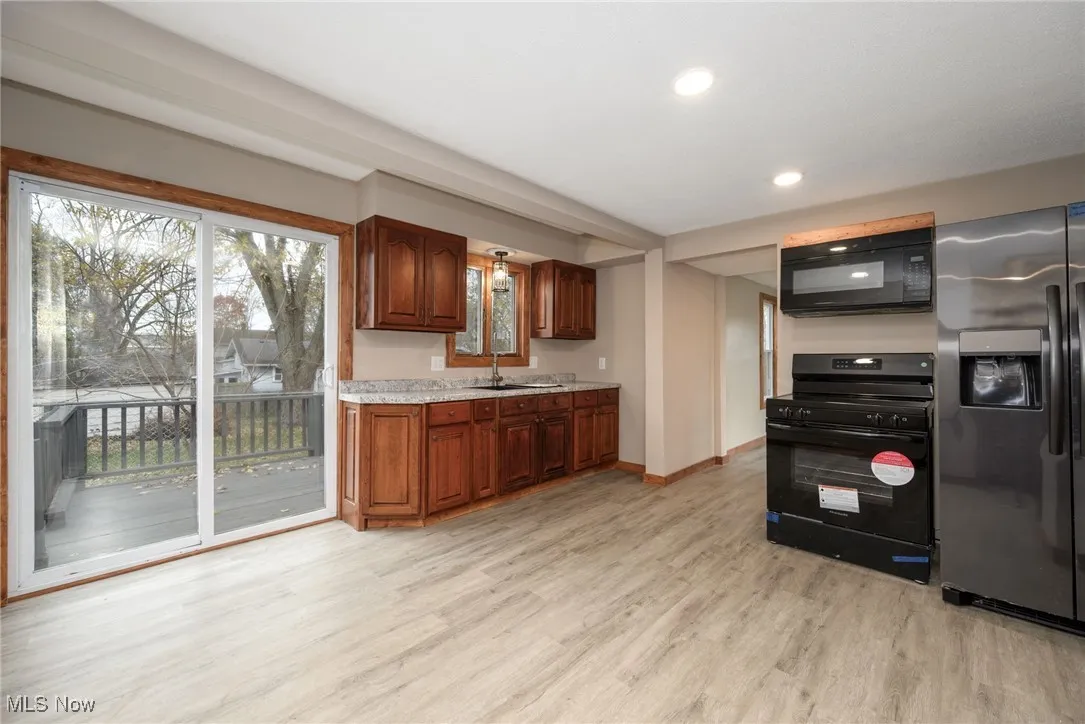 Kitchen featuring black appliances, recessed lighting, light wood-style floors, and light stone countertops