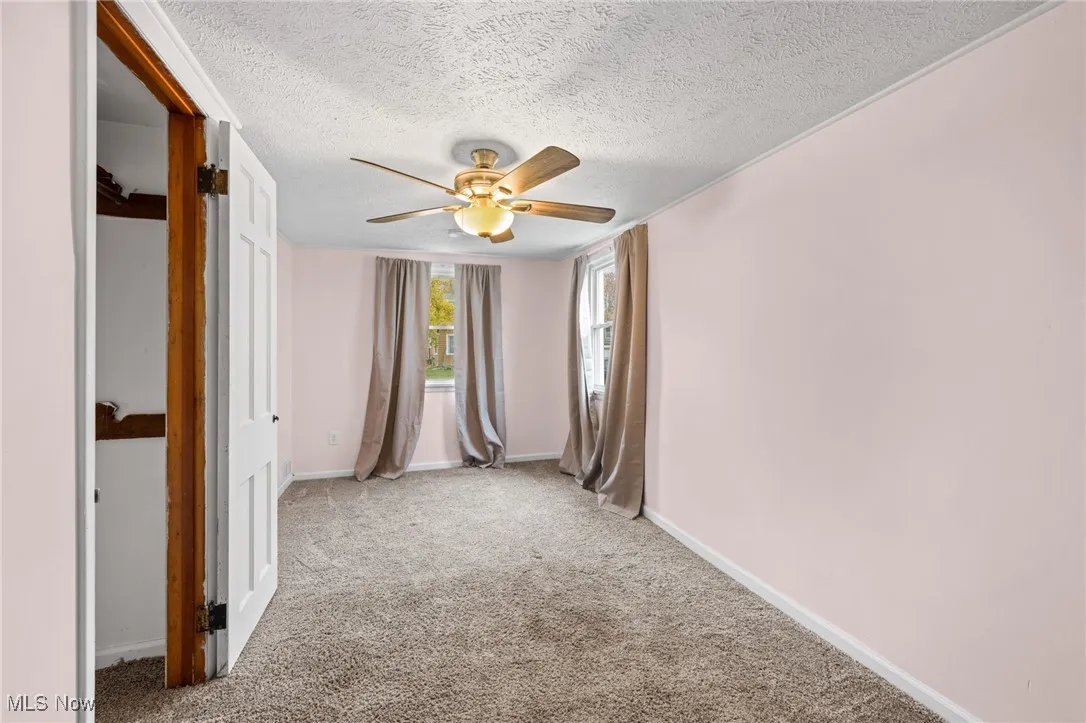 Carpeted bedroom  with a textured ceiling and ceiling fan