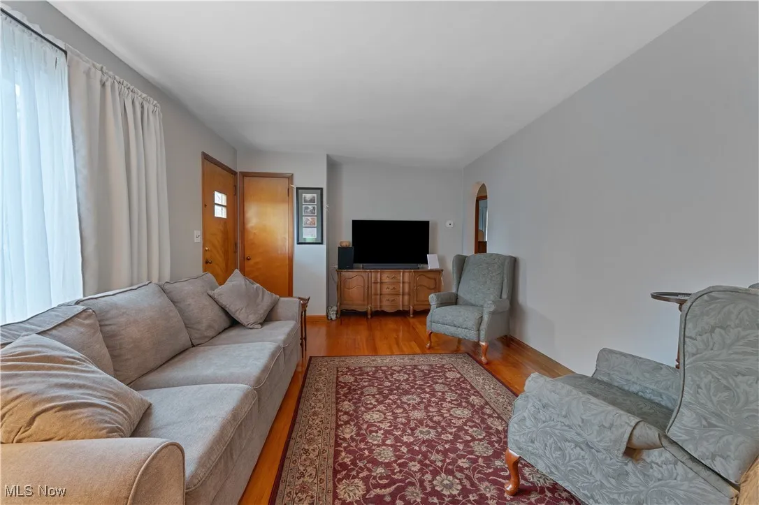Living room with arched walkways and wood finished floors