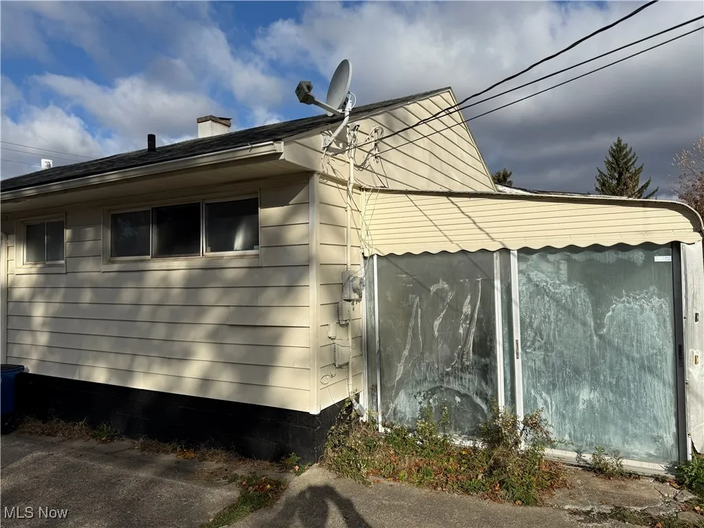 View of home's exterior featuring a chimney and a sunroom