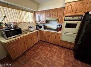 Kitchen featuring light countertops, stainless steel microwave, brown cabinets, and double oven