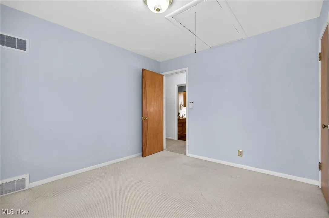 Carpeted empty room with baseboards and attic access