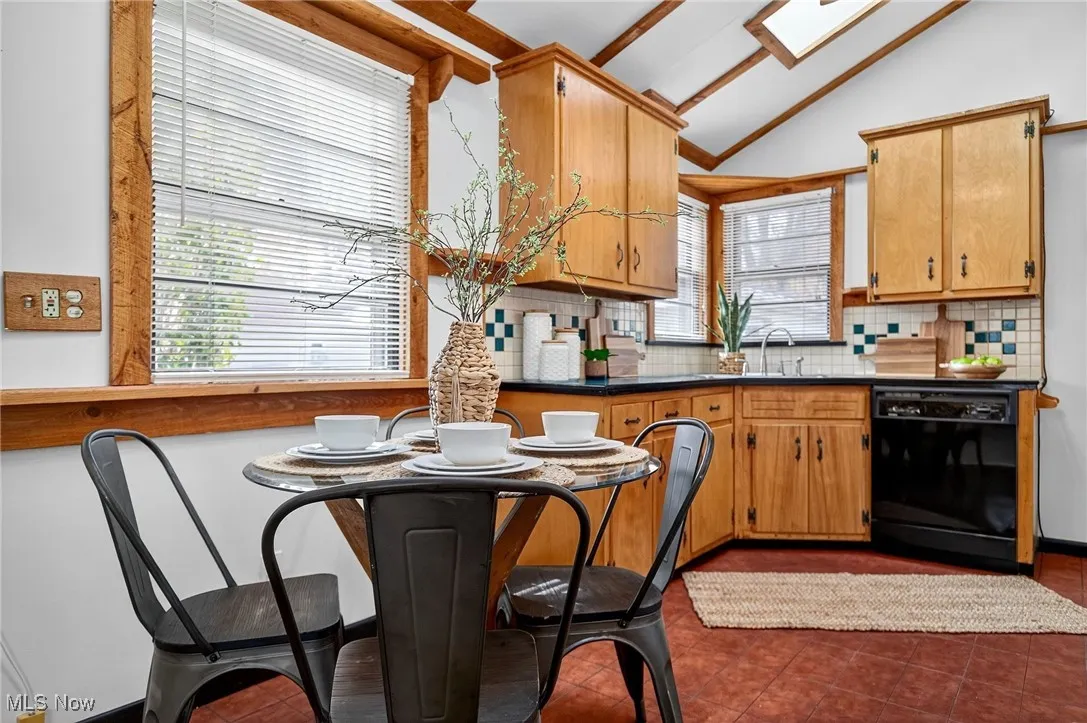 Kitchen featuring backsplash, dishwasher, dark countertops, and dark tile patterned flooring
