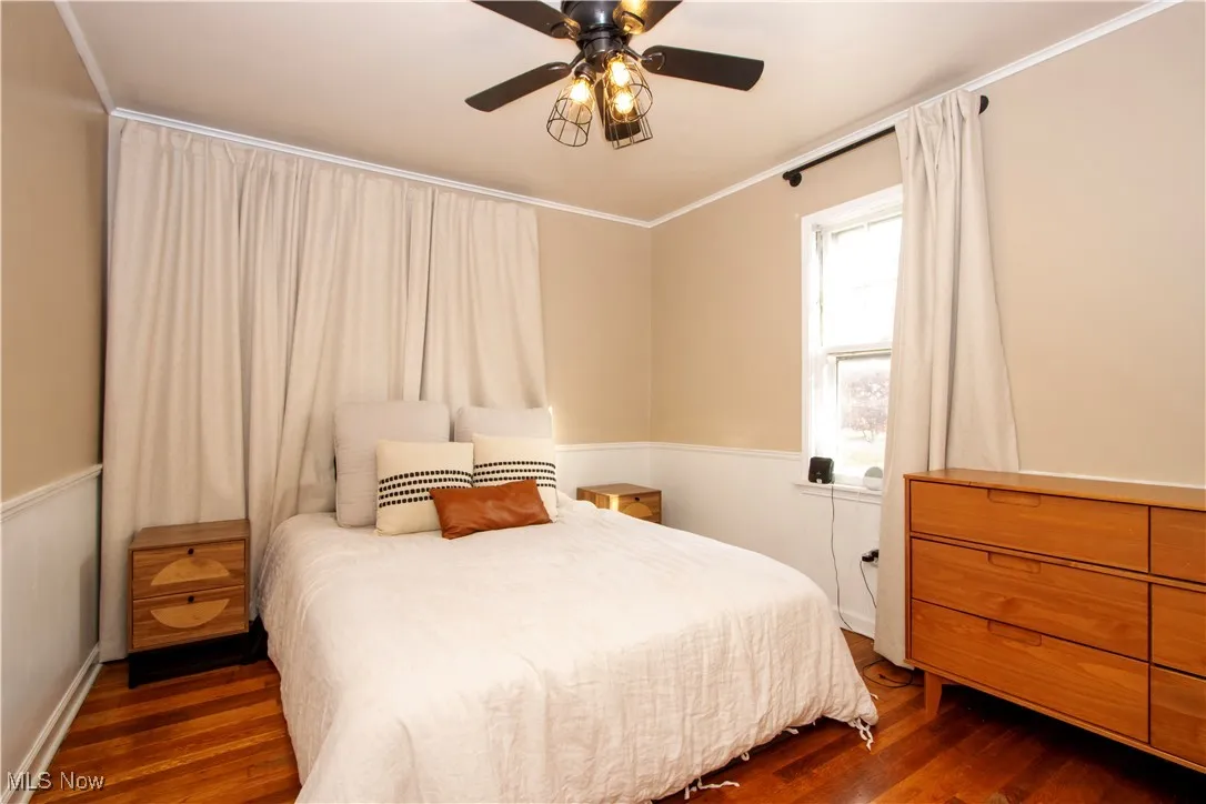 Bedroom featuring crown molding, dark wood-style flooring, and a ceiling fan
