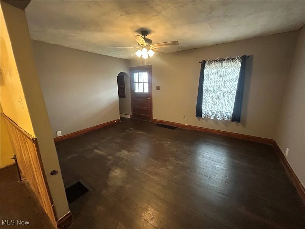 Foyer with dark wood-style flooring, arched walkways, and ceiling fan