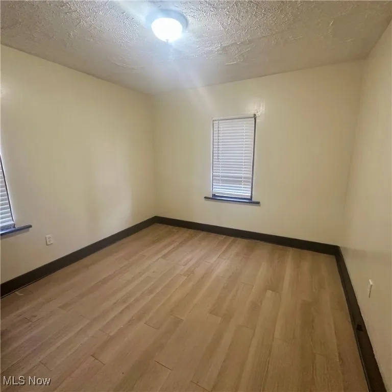 Unfurnished room with light wood-type flooring and a textured ceiling