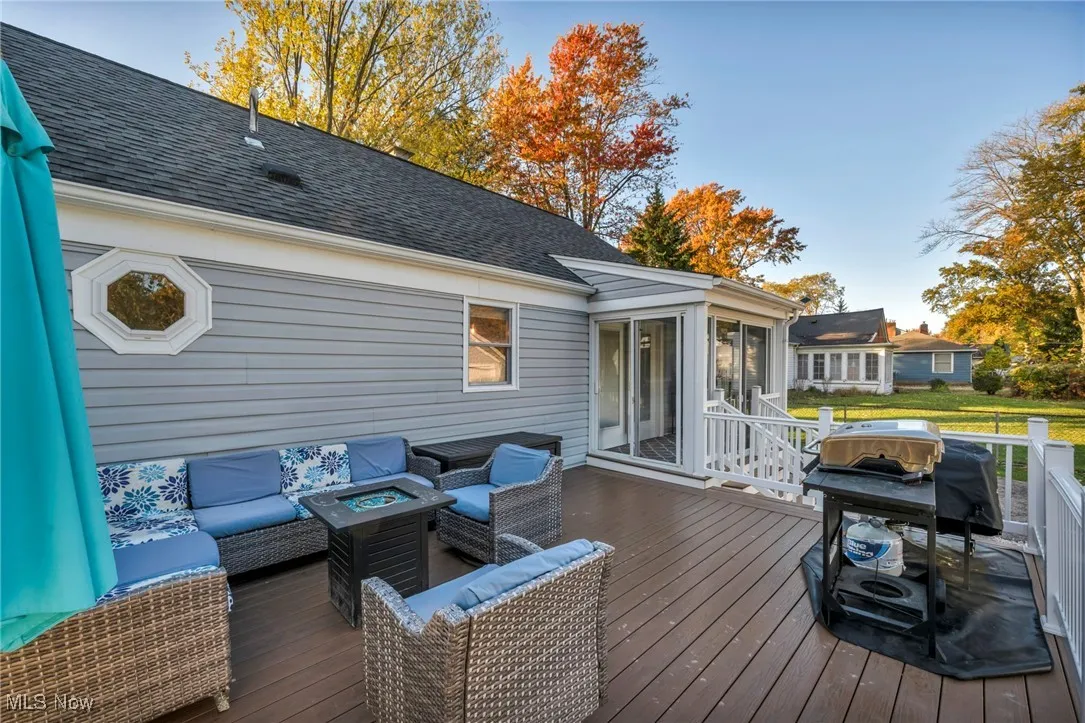 Wooden deck with grilling area, an outdoor living space with a fire pit, and a sunroom