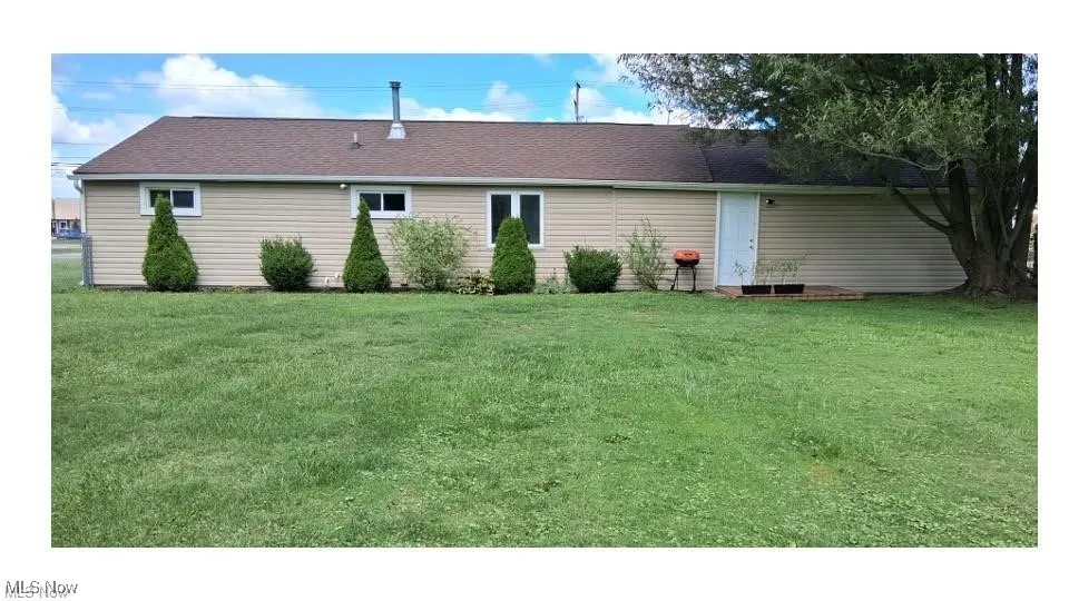 Rear view of property with a lawn and roof with shingles