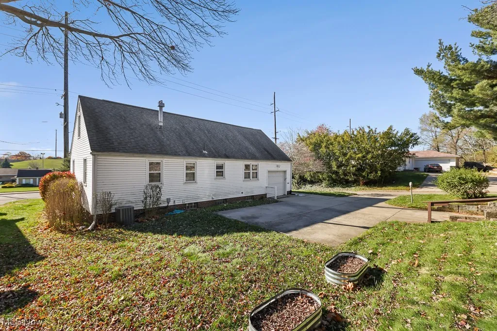 View of side of home with a lawn, concrete driveway, and a shingled roof