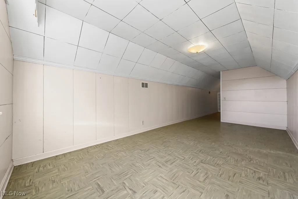 Additional living space with baseboards and vaulted ceiling