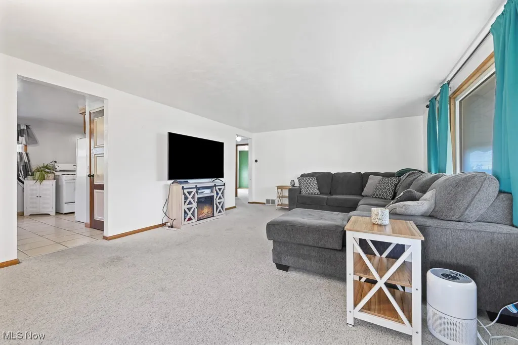 Living room with light colored carpet and light tile patterned flooring