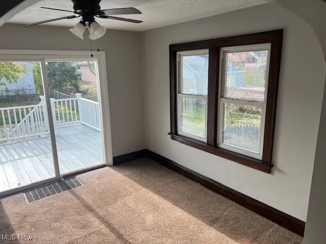 Carpeted spare room featuring a textured ceiling and a ceiling fan