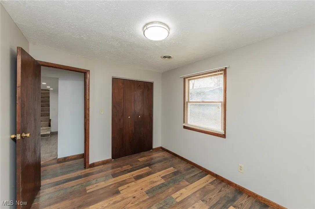 Unfurnished bedroom with dark wood-style flooring, a closet, and a textured ceiling