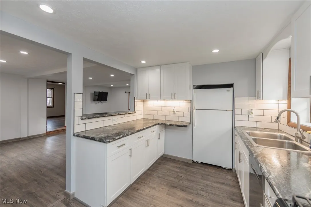 Kitchen with freestanding refrigerator, white cabinetry, dark wood finished floors, and recessed lighting