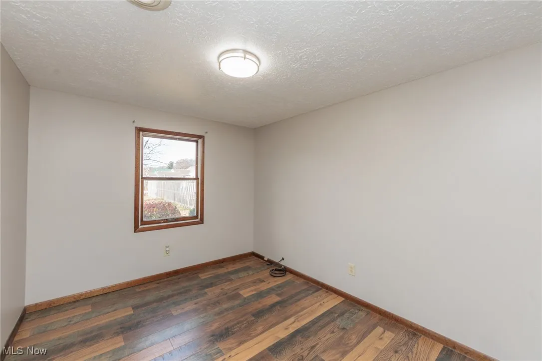 Empty room with dark wood-style floors and a textured ceiling
