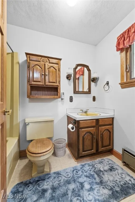 Full bathroom featuring vanity, a baseboard radiator, light tile patterned flooring, and shower / bathtub combination