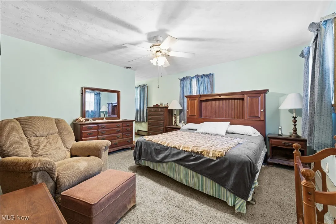 Carpeted bedroom featuring ceiling fan and a textured ceiling