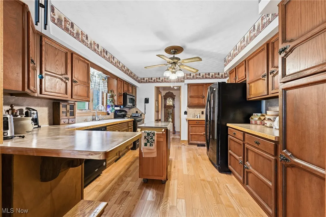 Kitchen with brown cabinetry, a kitchen island, and black appliances
