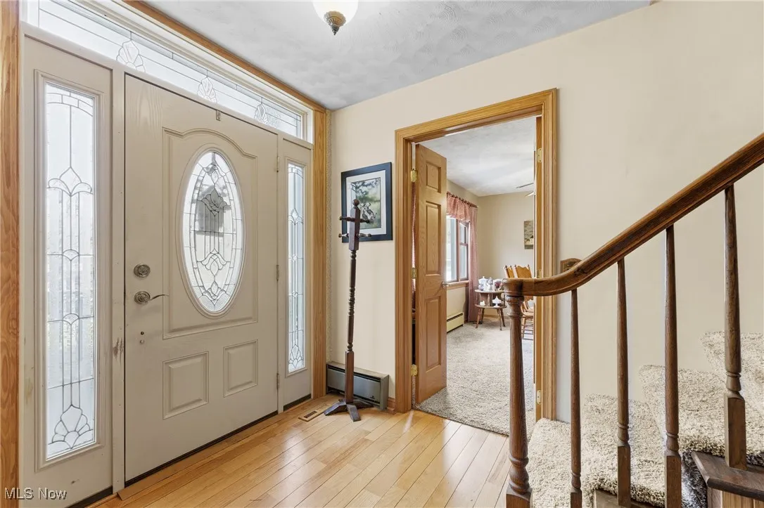 Foyer with healthy amount of natural light, a baseboard heating unit, and light wood finished floors