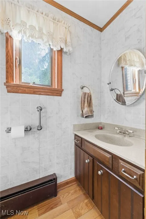 Bathroom with a light wood-type flooring, vanity, and ornamental molding