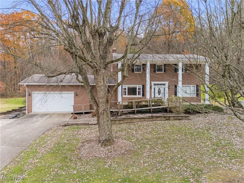 View of front of property featuring brick siding, driveway, and a garage