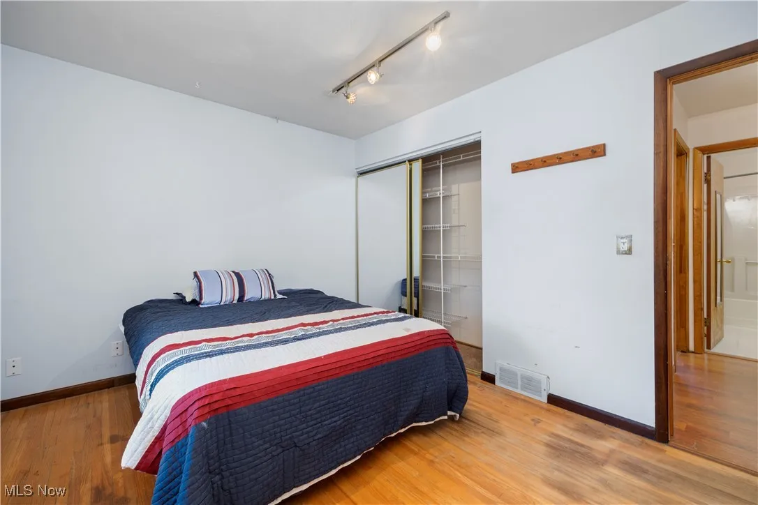 Bedroom with wood finished floors, a closet, and rail lighting