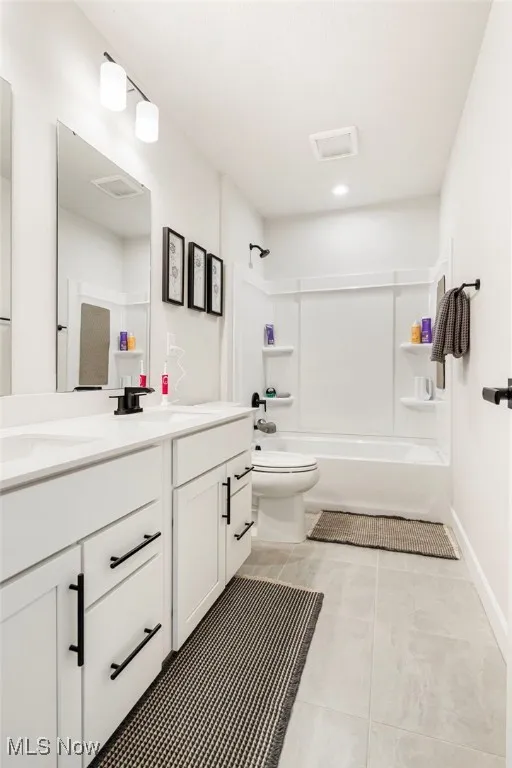 Bathroom with double vanity, light tile patterned flooring, and shower / washtub combination