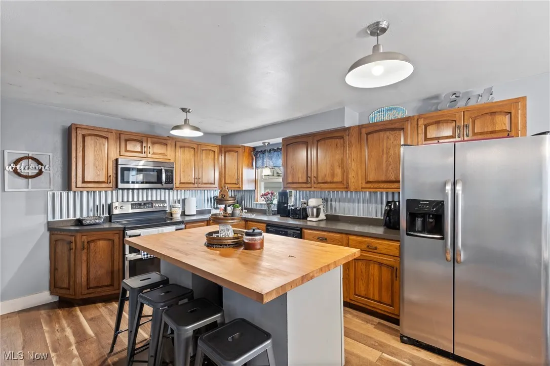Kitchen with appliances with stainless steel finishes, brown cabinetry, a breakfast bar area, and light wood-style flooring