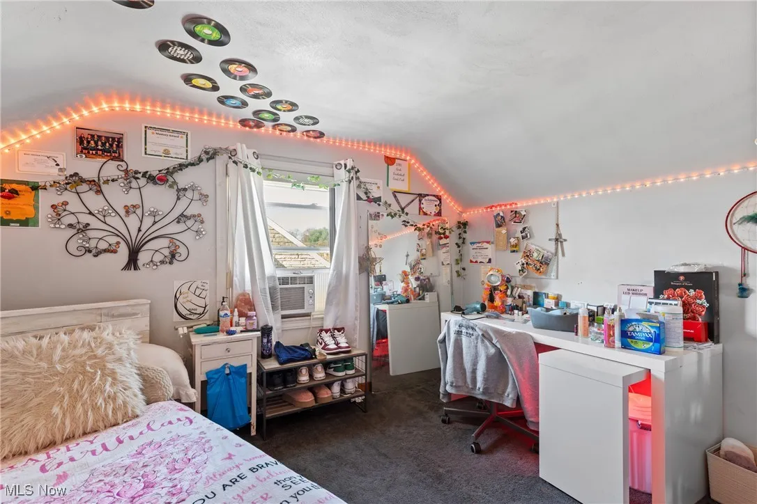 Bedroom with a desk, dark colored carpet, cooling unit, lofted ceiling, and white fridge