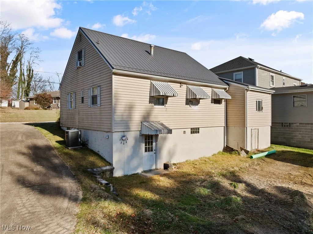 Back of house featuring a metal roof, a lawn, and a standing seam roof