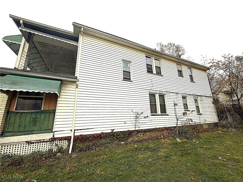 View of home's exterior with a lawn and a balcony