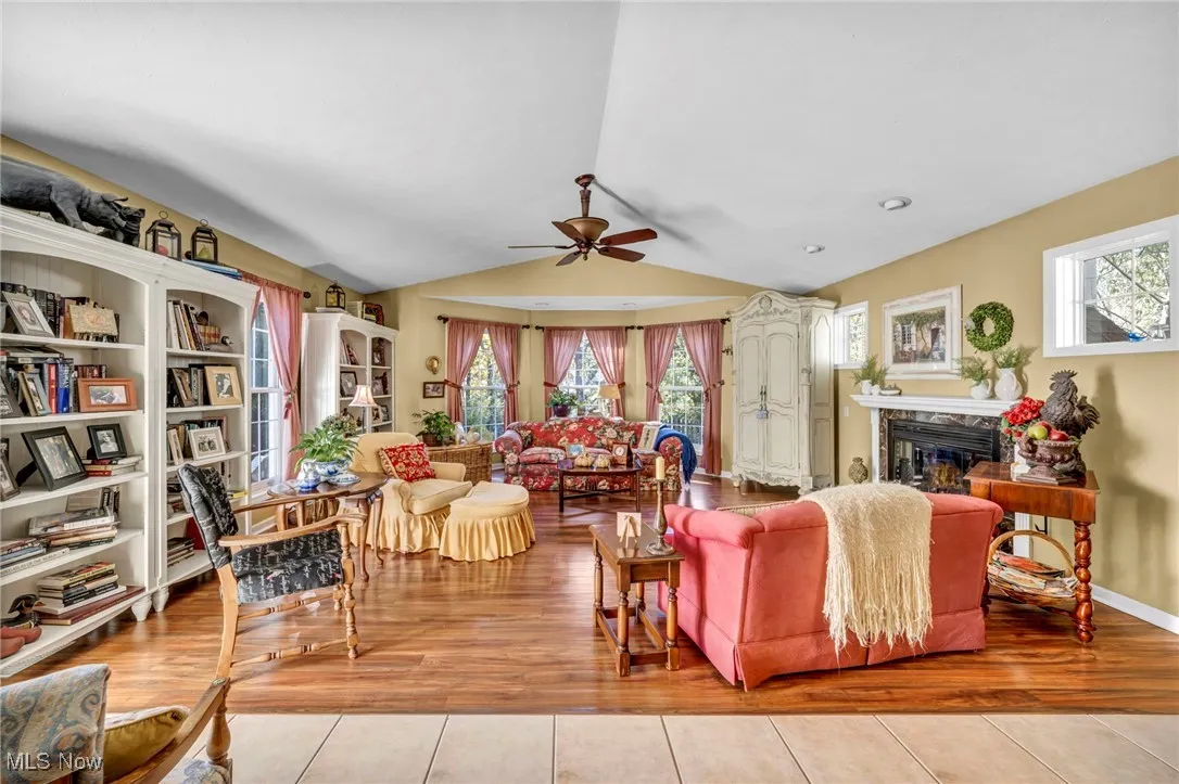 Living area with vaulted ceiling, a fireplace, ceiling fan, and wood finished floors