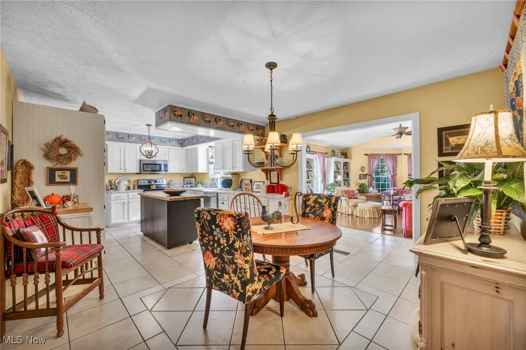Dining area featuring light tile patterned floors, a textured ceiling, and a chandelier