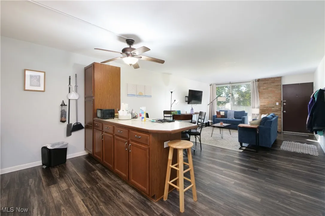 Kitchen with brown cabinets, light countertops, a peninsula, open floor plan, and a breakfast bar