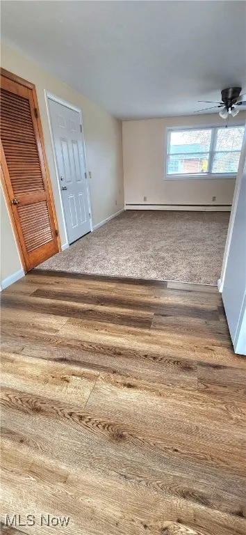 Unfurnished room with light wood-type flooring, ceiling fan, and baseboard heating