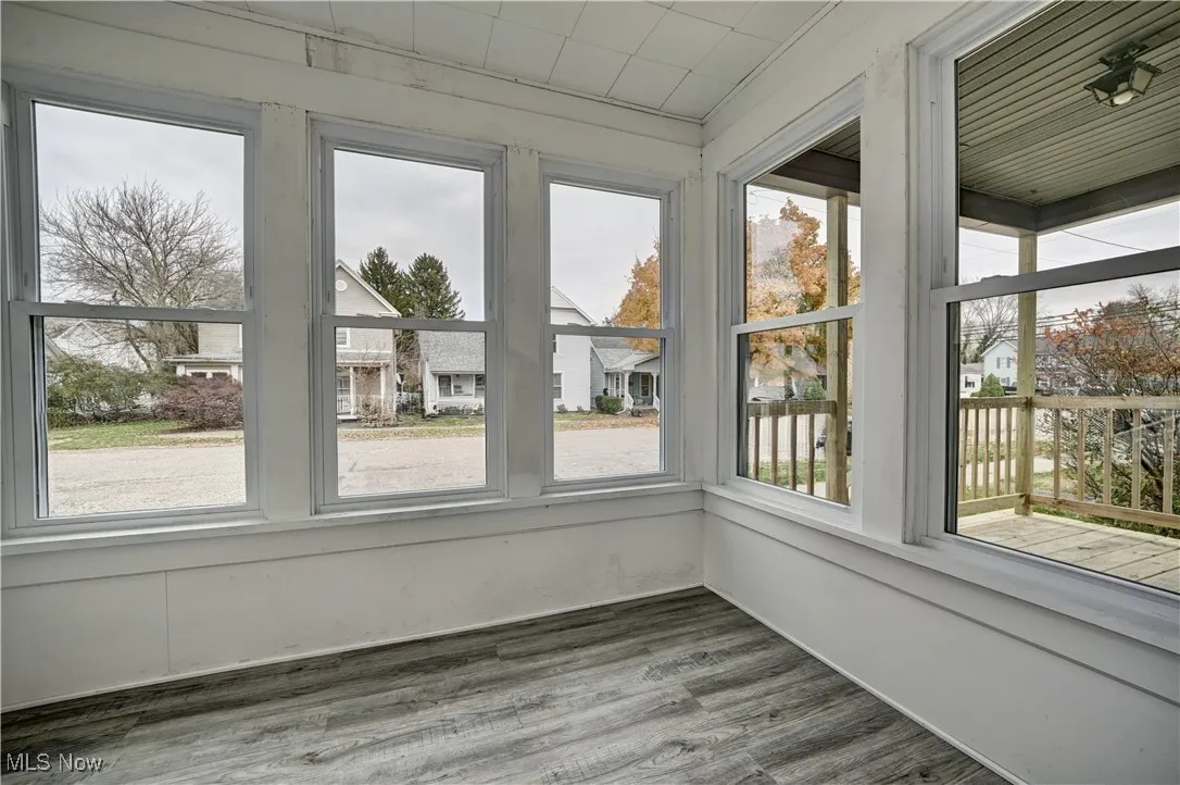Unfurnished sunroom featuring wood finished floors, plenty of natural light, and a residential view