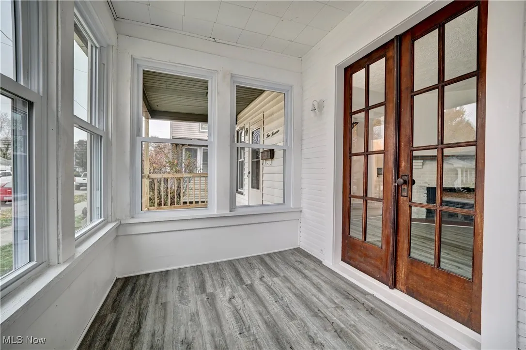 Unfurnished sunroom featuring wood finished floors, french doors, and plenty of natural light