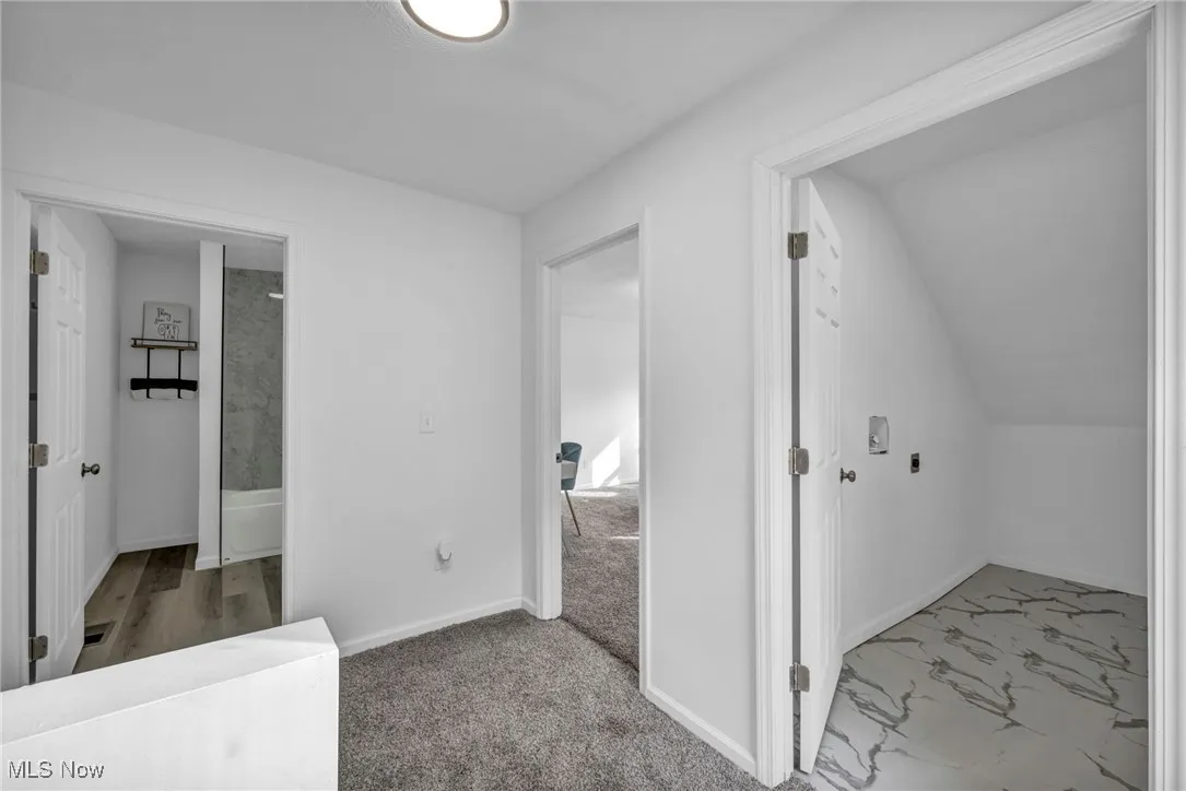 Hallway with baseboards and light colored carpet