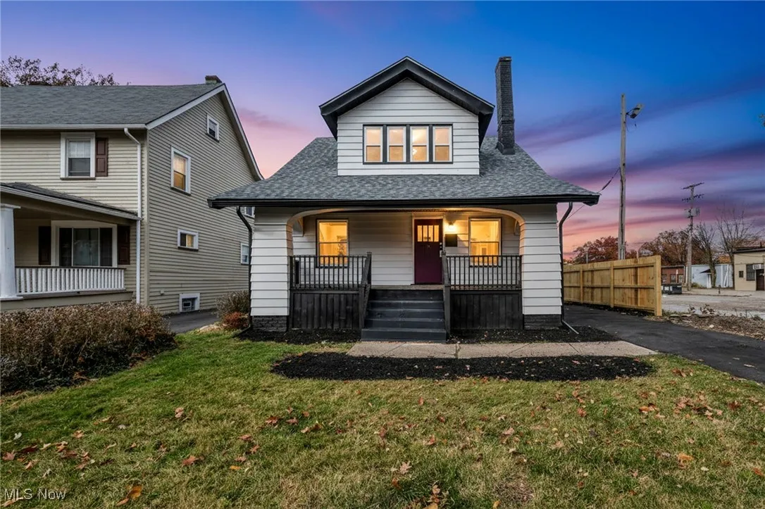 View of front of home with a porch, roof with shingles, a front yard, and a chimney